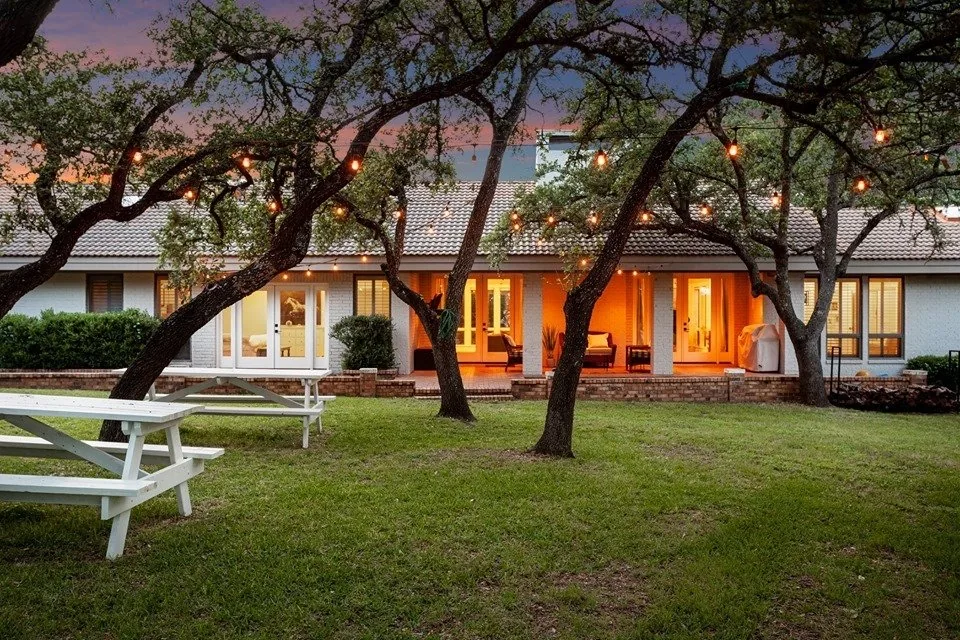 Hill Country home under oak trees at dusk, from the exteriors gallery