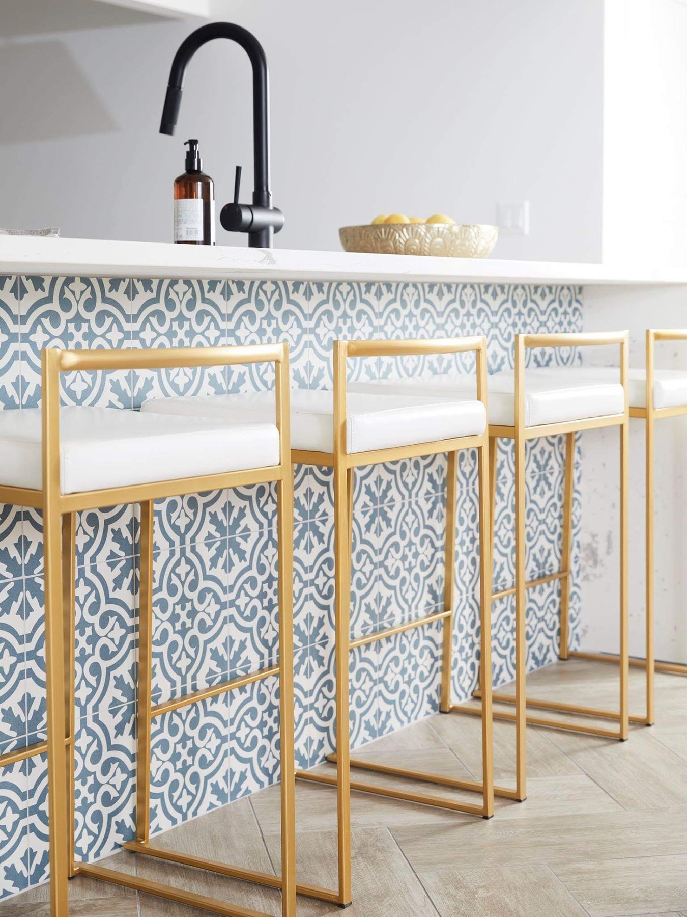 Kitchen bar detail with patterned tile and brass stools