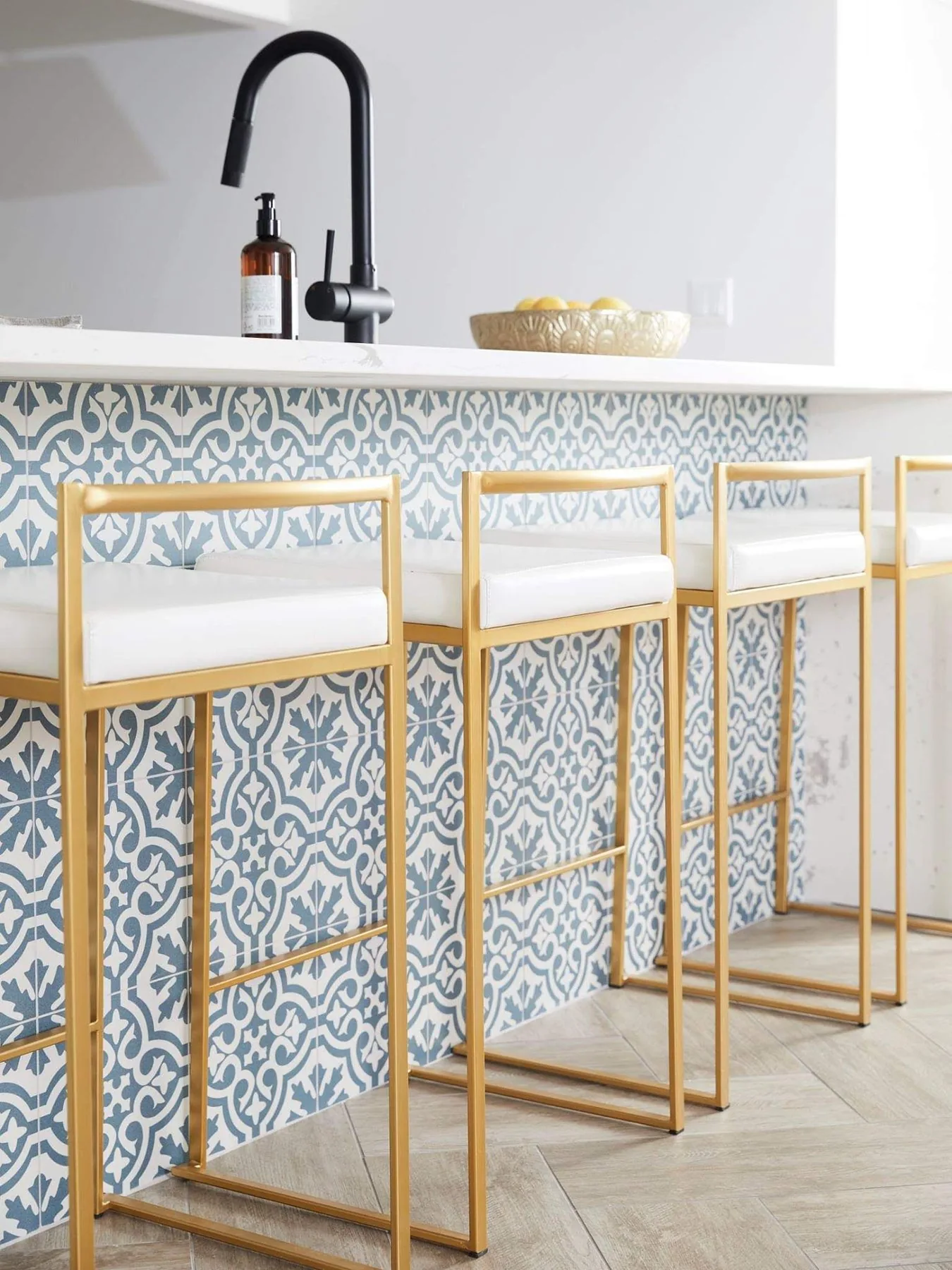 Kitchen bar detail with patterned tile and brass stools