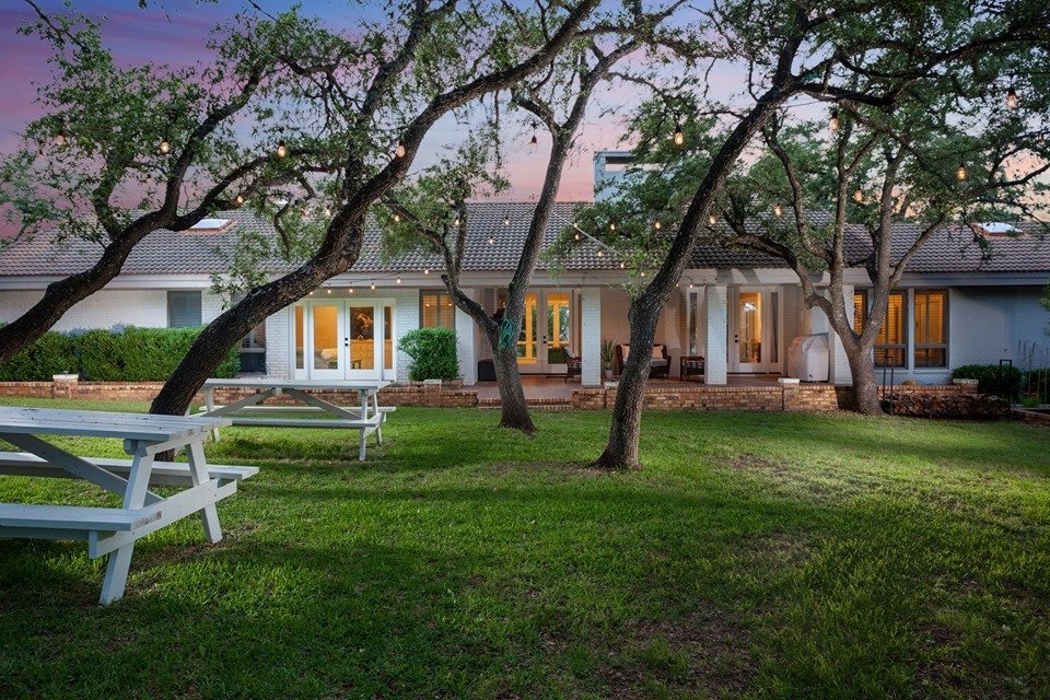 Hill Country home exterior at dusk with picnic tables