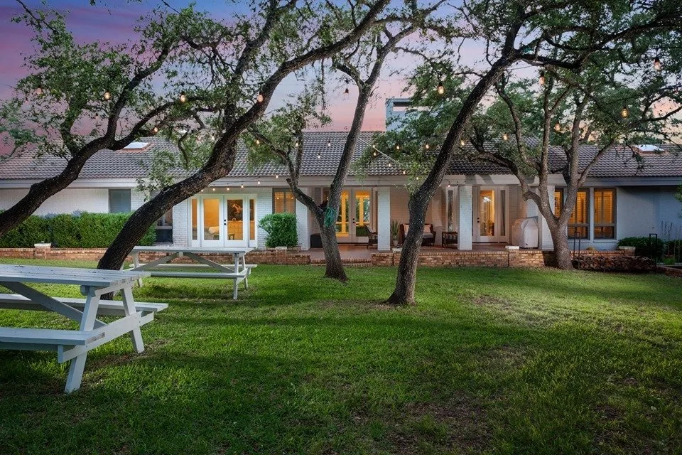 Hill Country home exterior at dusk with picnic tables